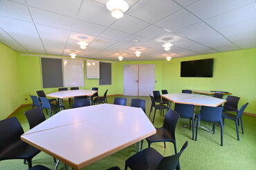 Tagungsraum mit mehreren Tischen und St&uuml;hlen